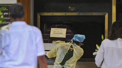 A worker places the coffin of Sri Lanka's former foreign minister Mangala Samaraweera, who died today due to Covid-19, in the furnace to be cremated at Colombo's main cemetery. AFP