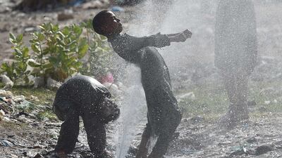People cool off at a water supply line as temperatures rise in Karachi, Pakistan. EPA