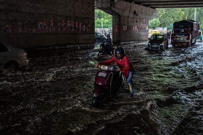 A man pushes his scooter through a waterlogged road after it rained in New Delhi, India, Thursday, Sept. 22, 2022. (AP Photo / Altaf Qadri)