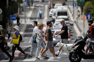 Pedestrians cross a street as Israel rescinds the mandatory wearing of face masks outdoors in the latest return to relative normality. Reuters / Amir Cohen