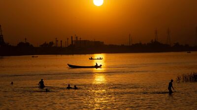 Iraqis swim in the Shatt Al-Arab river by the port of al-Maaqil amid a heatwave in the southern city of Basra, on July 2, 2021. - Anger has mounted among Iraq's 40-million population, with corrupt politicians at the centre of a blame game for its poor services and dilapidated infrastructure. Four southern provinces have been without electricity since June 29, including Basra -- home to Iraq's main port -- and sizzling temperatures have been compounded by high levels of humidity. (Photo by Hussein FALEH / AFP)