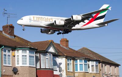 (FILES) In this file photo taken on February 18, 2015, An Emirates Airbus A380 aircraft is seen above roof top as it comes into lane at Heathrow Airport in west London. - Dubai-based Emirates airline today posted a $5. 5 billion annual loss, its first in more than three decades, after the coronavirus pandemic devastated the aviation industry. (Photo by Justin TALLIS / AFP)