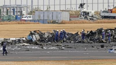 Firefighters gather around the burn-out Japanese coast guard aircraft at Haneda airport on Wednesday, Jan. 3, 2024, in Tokyo, Japan. Transport officials and police each began their on site investigation at Tokyo’s Haneda Airport on Wednesday after a large passenger plane and the Japanese coast guard aircraft collided on the runway and burst into flames, killing several people aboard the coast guard plane. (Kyodo News via AP)