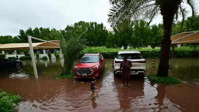 A woman and child stand in a flooded street in Dubai on May 2, 2024, as heavy rains returned to the United Arab Emirates just two weeks after record downpours that experts linked to climate change. (Photo by Giuseppe CACACE / AFP)