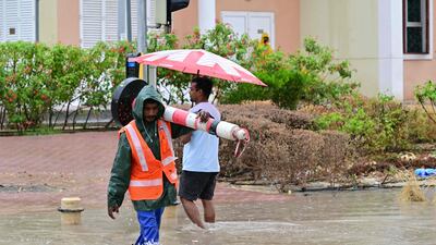 A municipal worker walks along a flooded street in Dubai on May 2, 2024, as heavy rains returned to the United Arab Emirates just two weeks after record downpours that experts linked to climate change. (Photo by Giuseppe CACACE / AFP)