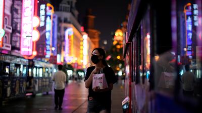 A woman wearing a protective mask walks on a street, following new cases of Covid-19, in Shanghai, China. Reuters