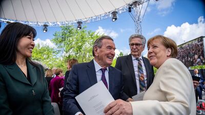 Angela Merkel, former Chancellor, right, and Gerhard Schröder, former Chancellor, center, take part in the state ceremony to mark "75 years of the Basic Law" at the forum between the Bundestag and the Federal Chancellery in Berlin, Thursday May 23, 2024. The Basic Law of the Federal Republic of Germany was promulgated on May 23, 1949 and came into force the following day. The anniversary will be celebrated with a three-day democracy festival from 24 to 26 May 2024 in Berlin's government district. (Michael Kappeler/dpa via AP)