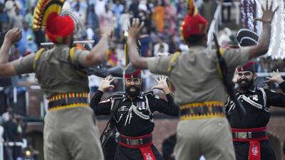 This picture taken on August 15, 2022, shows Indian Border Security Force (BSF) soldiers and Pakistani Rangers (in black) taking part in the Beating the Retreat ceremony during India's 75th Independence Day celebrations at the India-Pakistan Wagah border post, about 35km from Amritsar. (Photo by Narinder NANU / AFP)