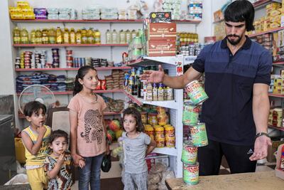 TOPSHOT - Palestinian performance artist Mohammed al-Shenbari stacks up packages of canned beans as he demonstrates his skills in balancing objects atop each other, in Beit Hanun in the northern Gaza Strip on July 6, 2021. - The self-taught 26-year-old artist says he can balance almost any object, through his training in fitness and body-building. (Photo by MOHAMMED ABED / AFP)