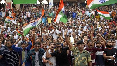This picture taken on August 15, 2022, shows visitors waving India's national flag at the Beating the Retreat ceremony during India's 75th Independence Day celebrations at the India-Pakistan Wagah border post, about 35km from Amritsar. (Photo by Narinder NANU / AFP)