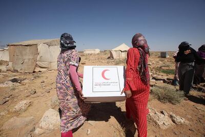 Syrian refugees carry off aid handed out by the Emirates Red Crescent as they head to their tent in north-east Jordan. Salah Malkawi / The National