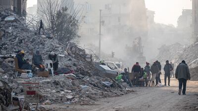 HATAY, TURKEY - FEBRUARY 13: People sit around a fire and walk past collapsed buildings on February 13, 2023 in Hatay, Turkey. A 7.8-magnitude earthquake hit near Gaziantep, Turkey, in the early hours of Monday, followed by another 7.5-magnitude tremor just after midday. The quakes caused widespread destruction in southern Turkey and northern Syria and were felt in nearby countries. (Photo by Burak Kara / Getty Images)