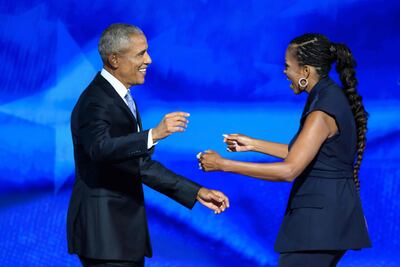 Former US President Barack Obama reaches out to embrace his wife and former First Lady, Michelle Obama, after she introduced him to the stage on the second day of the Democratic National Convention (DNC) at the United Center in Chicago, Illinois, on August 20, 2024. Vice President Kamala Harris will formally accept the party’s nomination for president at the DNC which runs from August 19-22 in Chicago. (Photo by MANDEL NGAN / AFP)