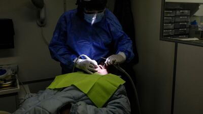 Doctor Neo Matlawe (back) of the Transnet-Phelophepa Healthcare Train offers dental care to a patient at the Dube Station in Soweto, on June 22, 2021. - The Transnet-Phelophepa is custom-built trains that deliver primary health care to remote areas of South Africa. (Photo by Phill Magakoe / AFP)