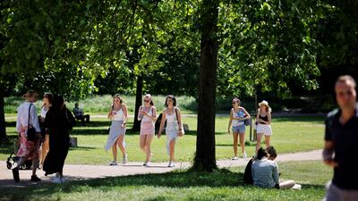 People walk in the sunshine in Hyde Park in London. The UK government has delayed the full lifting of coronavirus restrictions in England owing to a surge of infections caused by the Delta variant. AFP