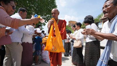 A Buddhist monk receives alms from devotees during the Buddhist Visak Bochea at Praseth Leu pagoda in northwest of Phnom Penh, Cambodia, Wednesday, May 22, 2024. (AP Photo/Heng Sinith)