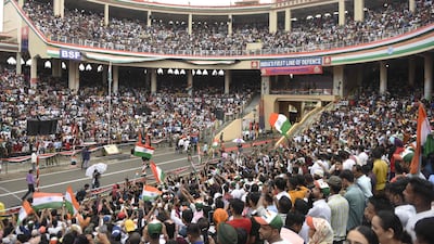 This picture taken on August 15, 2022, shows visitors waving India's national flag at the Beating the Retreat ceremony during India's 75th Independence Day celebrations at the India-Pakistan Wagah border post, about 35km from Amritsar. (Photo by Narinder NANU / AFP)
