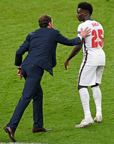 England manager Gareth Southgate touches the shoulder of England's Bukayo Saka during the Euro 2020 final soccer match between Italy and England at Wembley stadium in London, Sunday, July 11, 2021. (Facundo Arrizabalaga / Pool via AP)