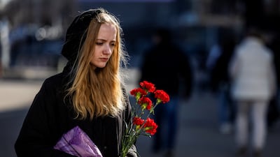 A woman walks to lay flowers at a makeshift memorial near the Crocus City Hall following last Friday's deadly attack on the concert venue in Moscow. Reuters