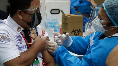 A security guard is inoculated with China's Sinovac COVID-19 vaccine at the Navotas Fish Port, Philippines on Monday, June 7, 2021. The government today bolstered its vaccination program by including frontline economic personnel both in private and government sectors. (AP Photo/Aaron Favila)