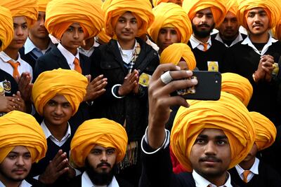 Sikh boys take a selfie using a mobile phone during a national level Turban tying event held at the Golden Temple in Amritsar on December 18, 2022. (Photo by Narinder NANU / AFP)
