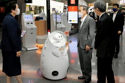 Japanese Prime Minister Yoshihide Suga stands by a remotely-controlled guide robot at Haneda international airport in Tokyo. AP Photo