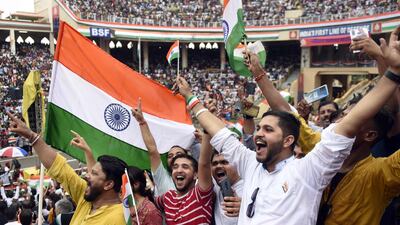 This picture taken on August 15, 2022, shows visitors waving India's national flag at the Beating the Retreat ceremony during India's 75th Independence Day celebrations at the India-Pakistan Wagah border post, about 35km from Amritsar. (Photo by Narinder NANU / AFP)