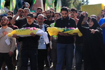 A woman, right, mourns as other carry the bodies of two kids, killed on Monday evening in an Israeli airstrike, during a mass funeral in Saksakiyeh village, south Lebanon, Wednesday, Nov. 13, 2024. (AP Photo / Mohammed Zaatari)